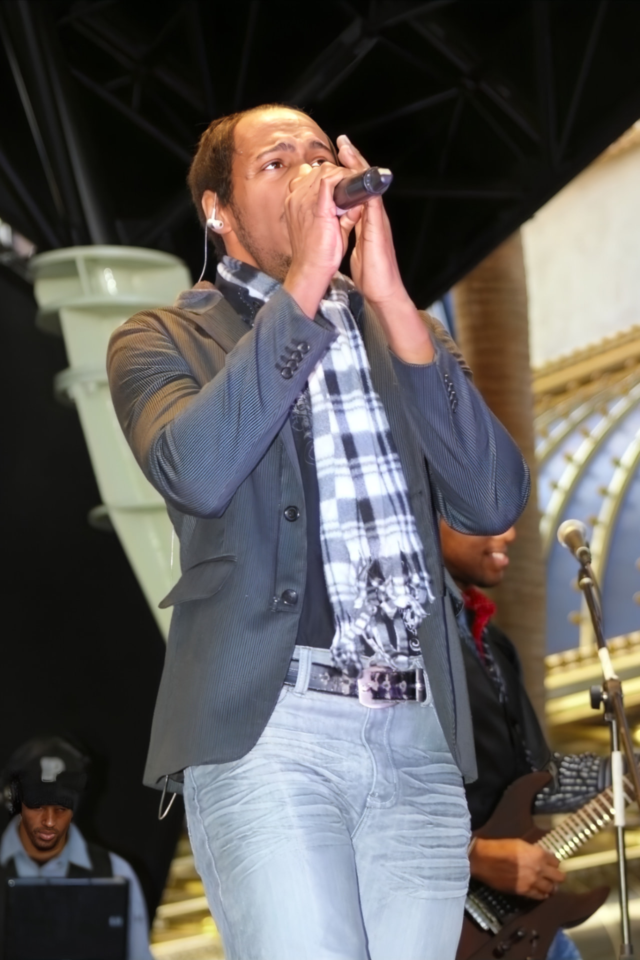 Reginald of PAR~A~DIGM singing into a handheld microphone on stage